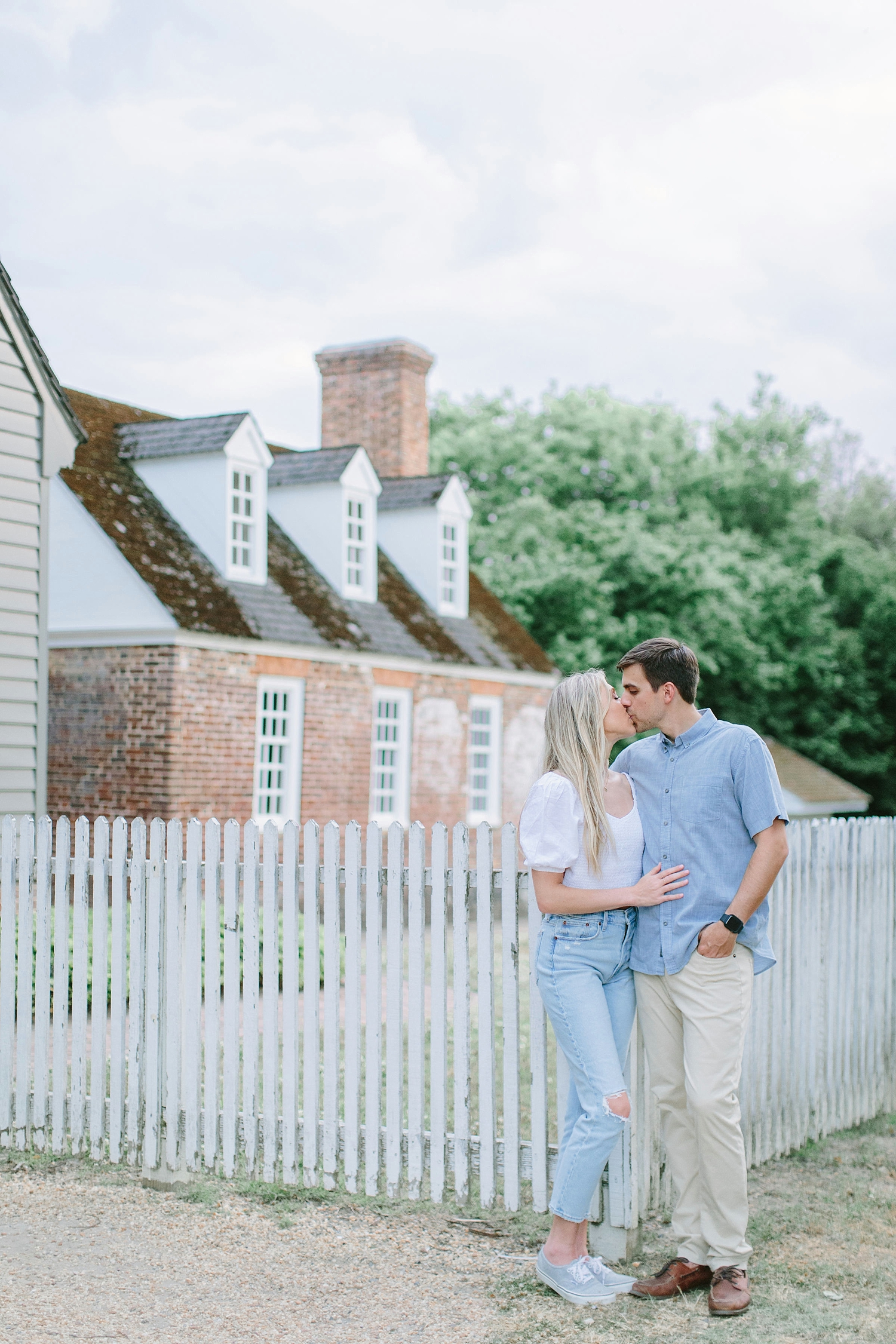Couple kissing in front of a fence in historic colonial williamsburg